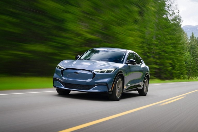 Une Mustang Mach E roule sur une route à deux voies