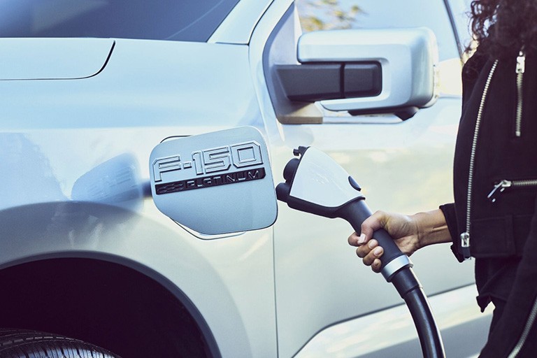 Une main insère un câble dans le port de charge d'un Ford F 150 Lightning