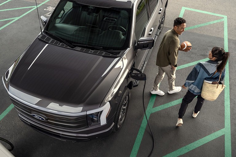 Un couple s'éloigne d'un F 150 Lightning garé à une station de recharge.
