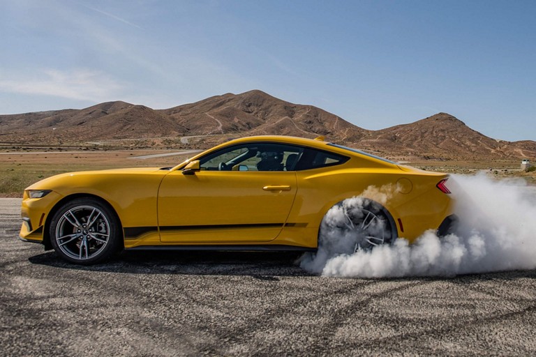 Une Ford Mustang avec des pneus qui tournent sur une chaussée pavée.