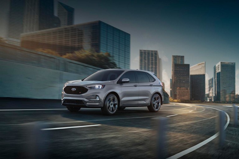 Un Ford Edge ST roule dans une rue urbaine en soirée