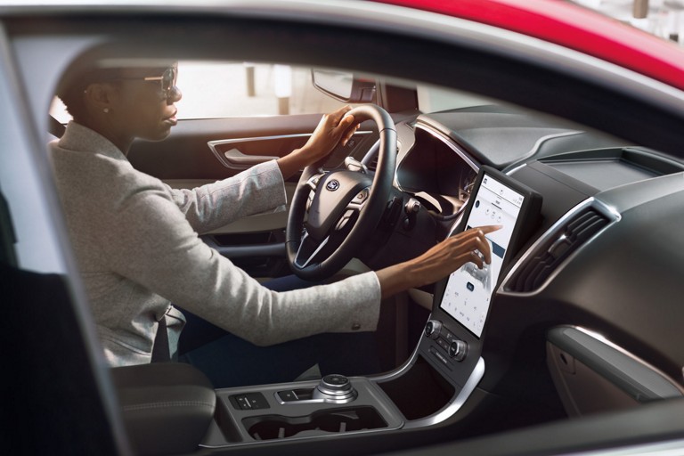 Une femme utilise l'écran tactile de 12 pouces dans un Ford Edge