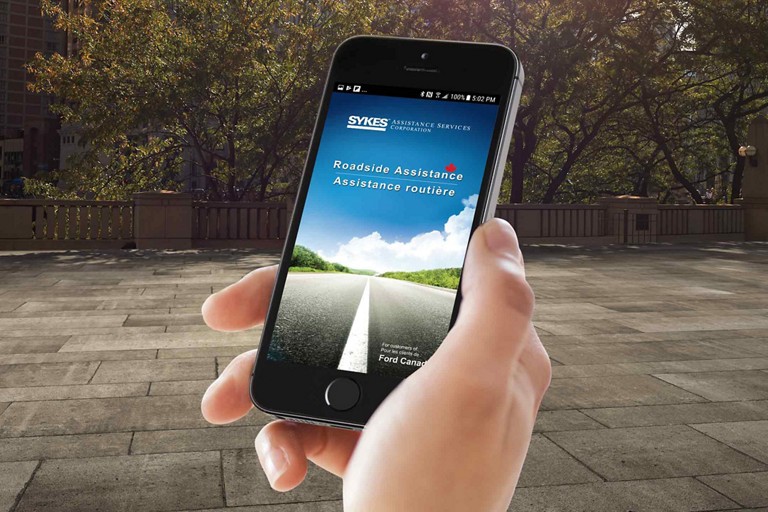 Main qui tient un téléphone portable et qui utilise l'application d’Assistance routière