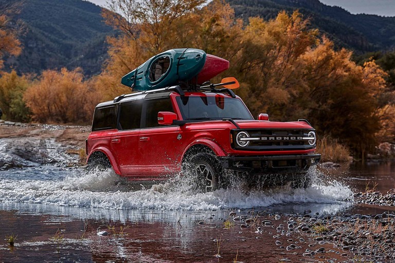 Un Ford Bronco traverse à gué une petite étendue d’eau.