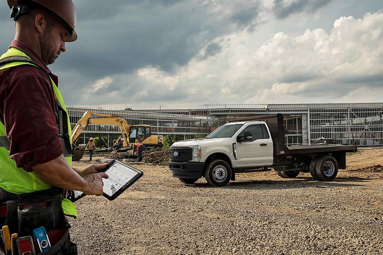 Un Ford Super Duty® F-350® 2025 sur un chantier alors qu’un homme utilise une tablette