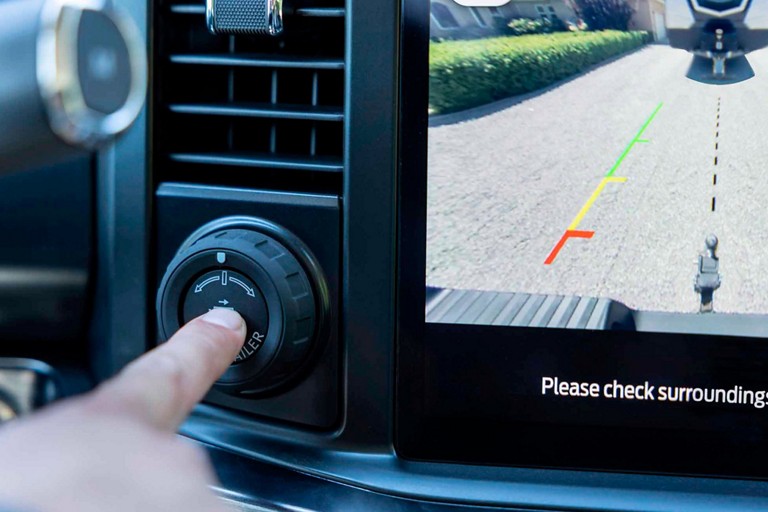 Gros plan d’une main appuyant sur le bouton Pro Trailer Hitch Assist™