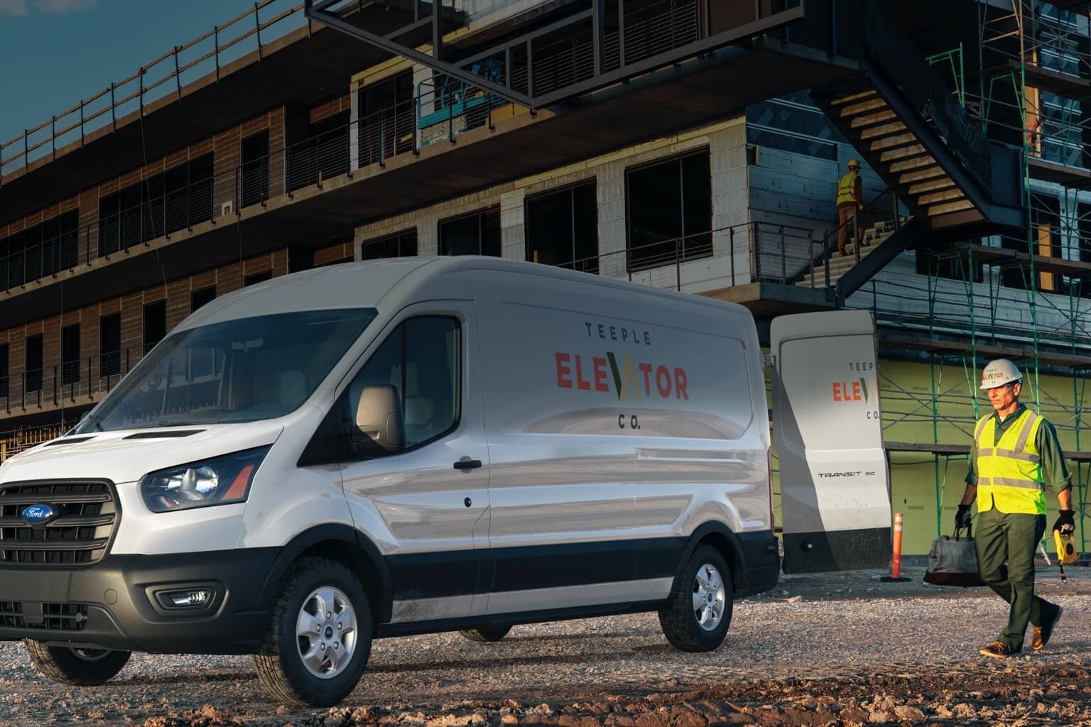 Des travailleurs de la construction sur un chantier près d’un Ford Transit 2020 en blanc platine avec les portes arrière ouvertes