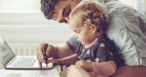 Travailleur travaillant de la maison devant un ordinateur portable avec un bébé sur les genoux