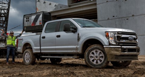Ouvriers derrière un camion Ford argenté sur un chantier.