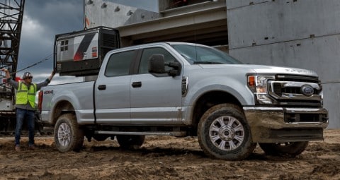 Ouvriers derrière un camion Ford argenté sur un chantier.