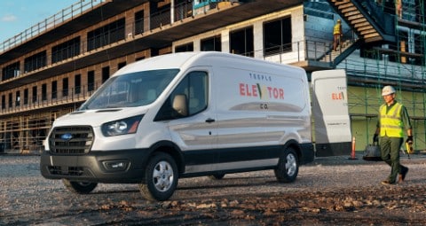 Des travailleurs de la construction sur un chantier près d’un Ford Transit 2020 en blanc platine avec les portes arrière ouvertes