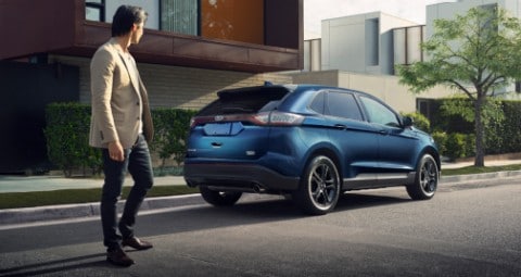 Homme passant à côté d’un Ford Edge dans la rue.
