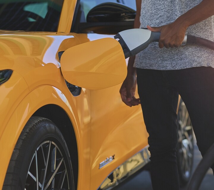 Une personne rechargeant sa Mustang Mach E 2021 à une station de recharge publique