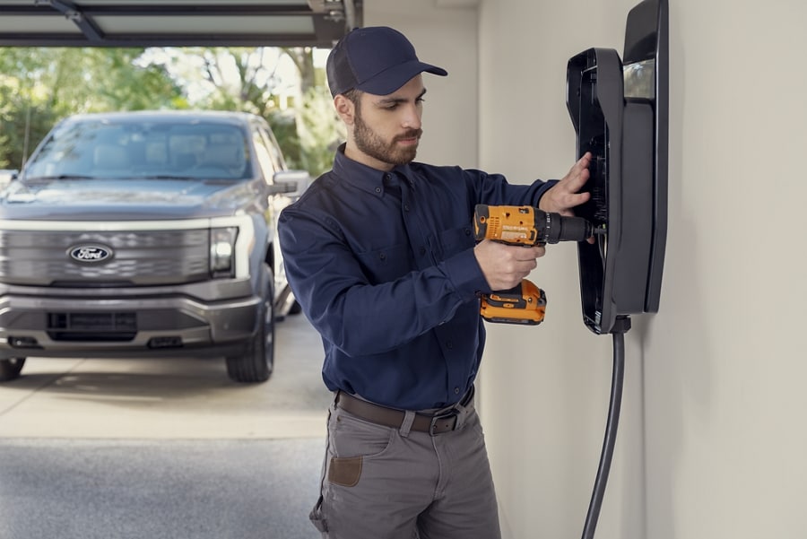 Technicien de service installant un chargeur domestique dans un garage résidentiel