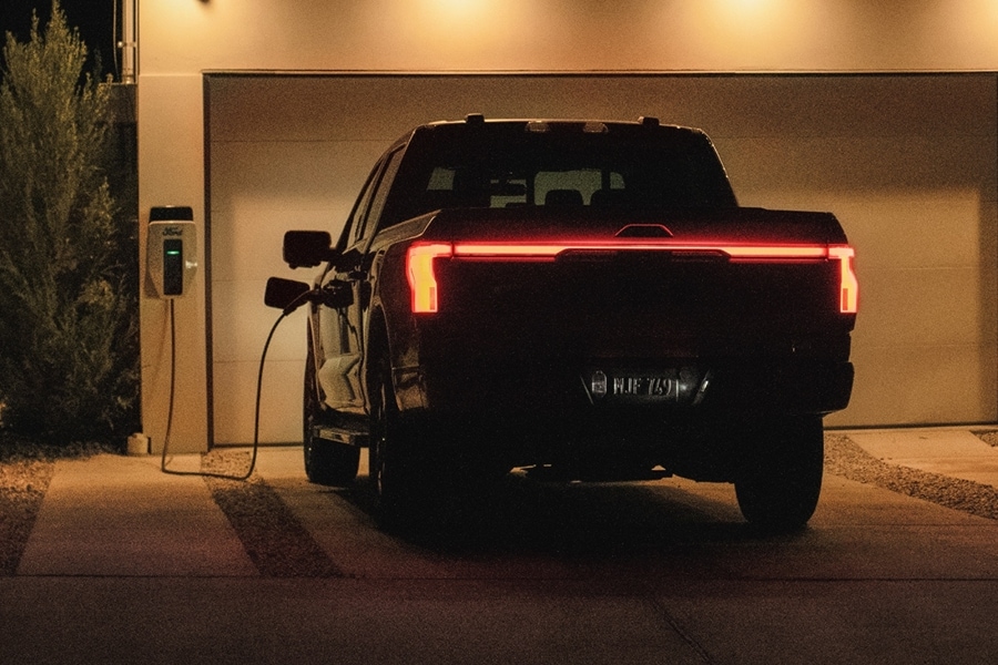 F-150 Lightning garé dans une allée résidentielle et branché à une borne de recharge domestique.