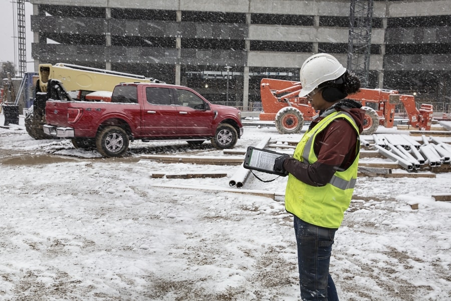 Une femme entrepreneur sur un chantier enneigé avec, en arrière-plan, un Ford F-150® 2022 de couleur rouge rapide