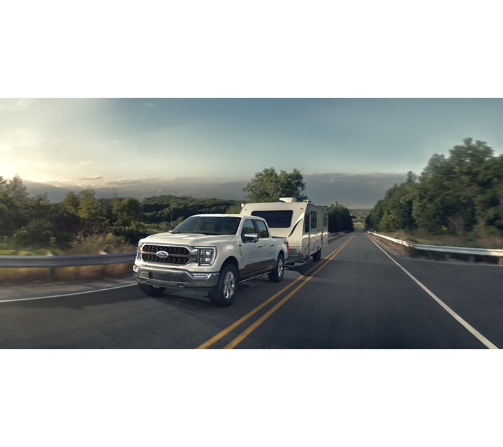 Ford F-150® LARIAT 2023 en noir agate reculant d’une remorque de bateau dans un lac