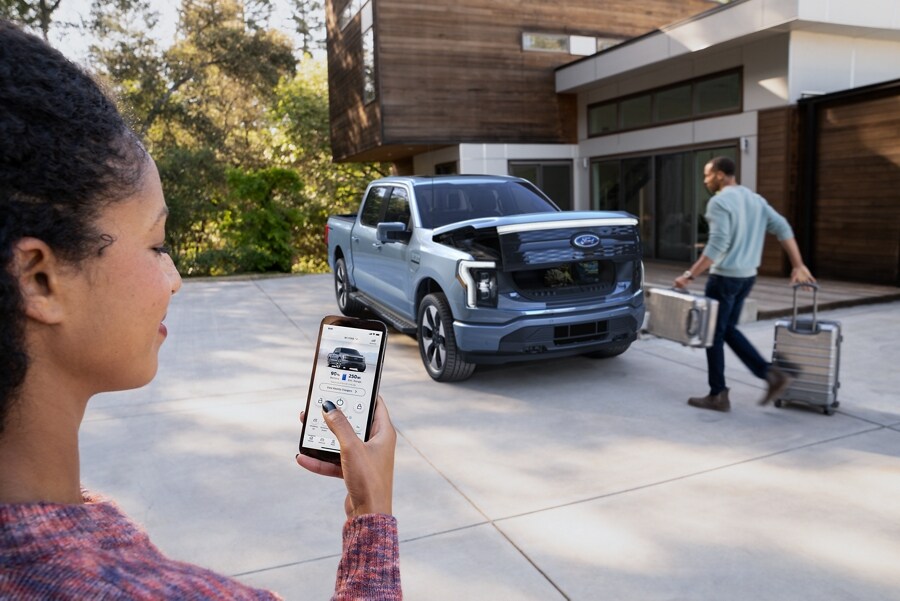 Gros plan d’une femme utilisant l’application FordPass™ pour ouvrir le coffre avant du Ford F-150® Lightning™