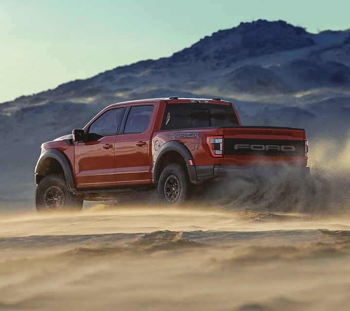 Le Ford Raptor® 2023 en rouge vif soulevant du sable sur une dune