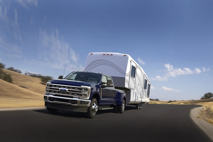 Modèle Ford Super Duty® F-250® Lariat® 2026 bleu argon roulant sur une autoroute pavée tout en tirant une caravane.