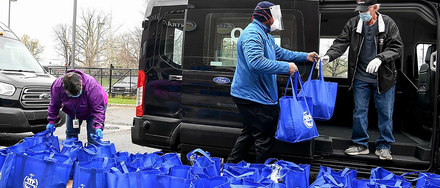 Des personnes mettent des sacs bleus dans un Ford Transit