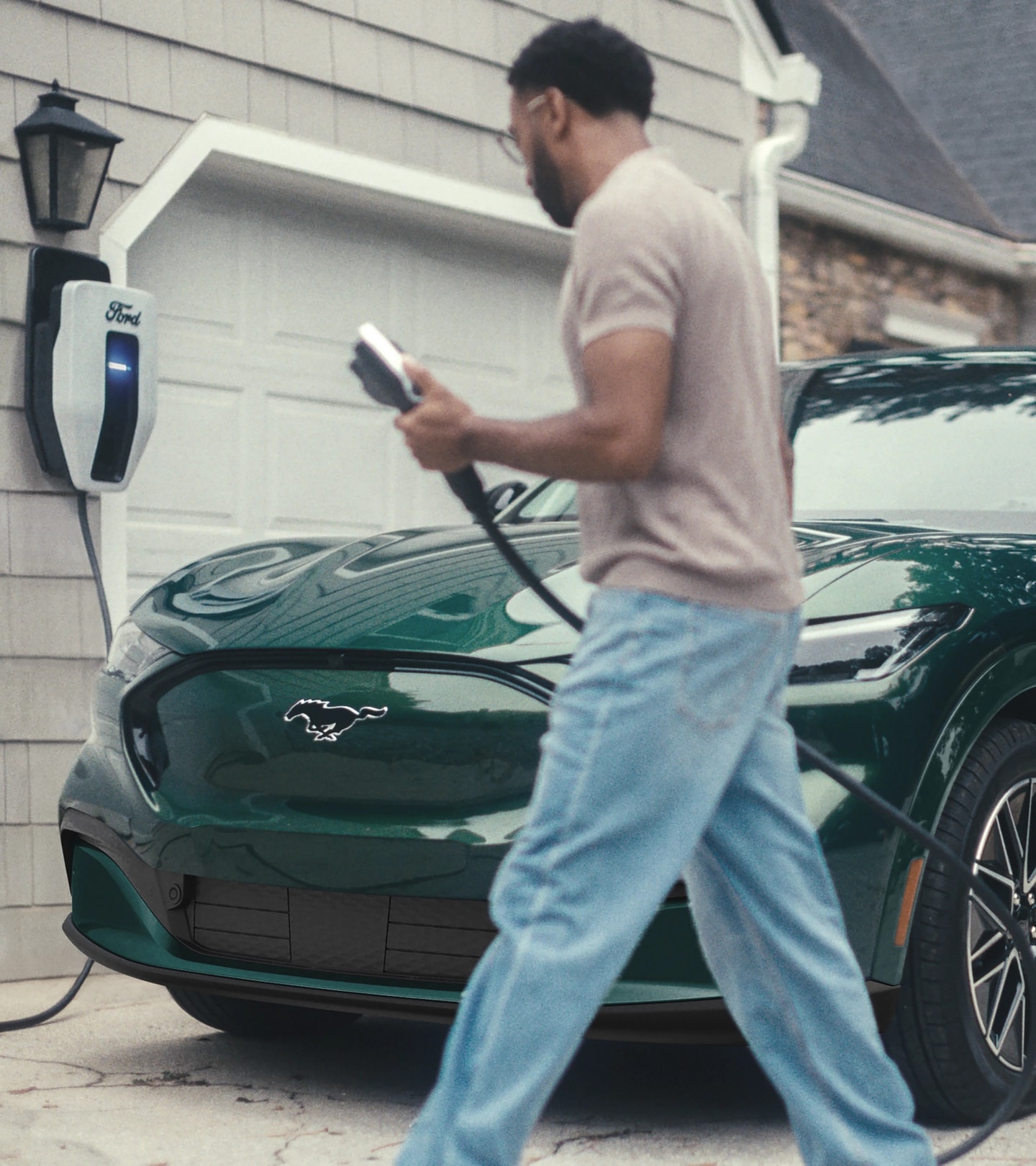 Un homme tient un câble de recharge pour VE près d’une Ford Mustang Mach-E.