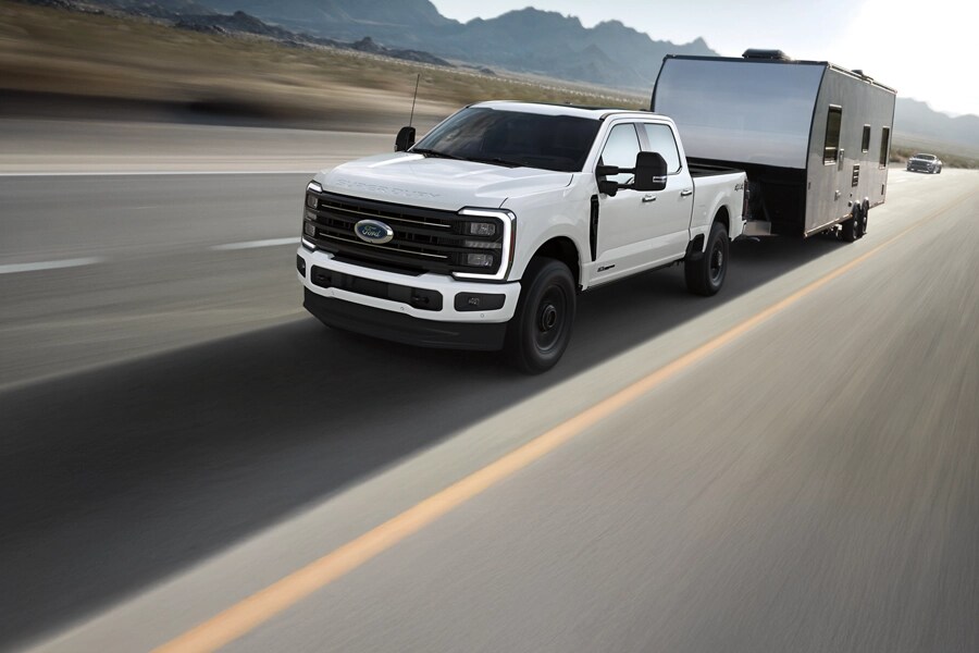 Un Ford blanc tire une caravane de camping sur une autoroute.