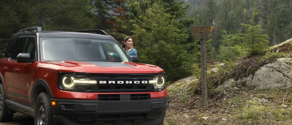 Ford Bronco Sport® 2025 stationné près d'arbres avec une femme debout à l'extérieur du véhicule