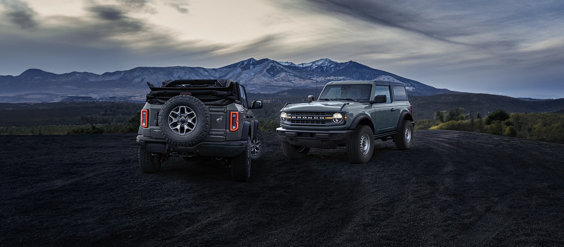 Deux VUS Ford Bronco® 2025 stationnés près d’une montagne enneigée, face à des directions opposées, illustrant deux toits en option