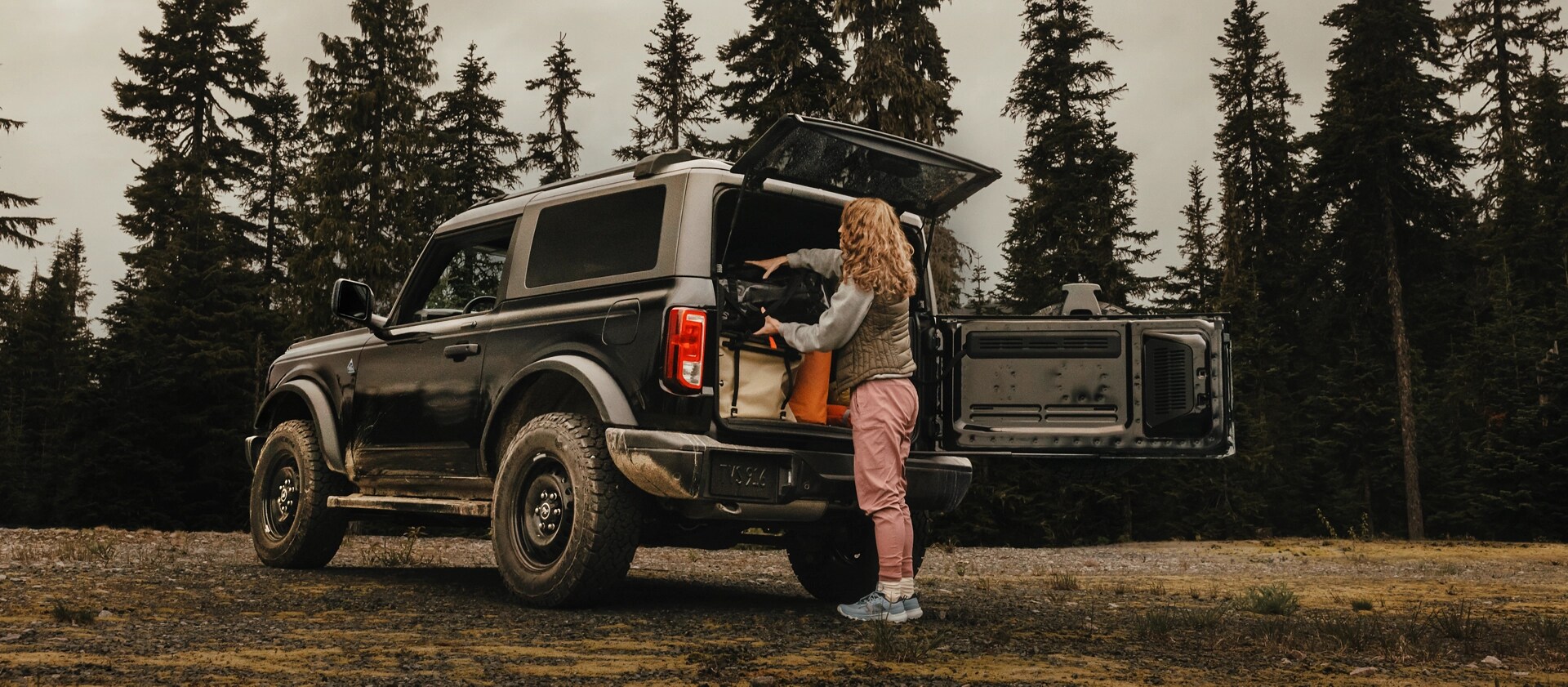 Une femme déchargeant de l’équipement de l’arrière d’un VUS Ford Bronco® 2025, montrant le hayon à ouverture latérale