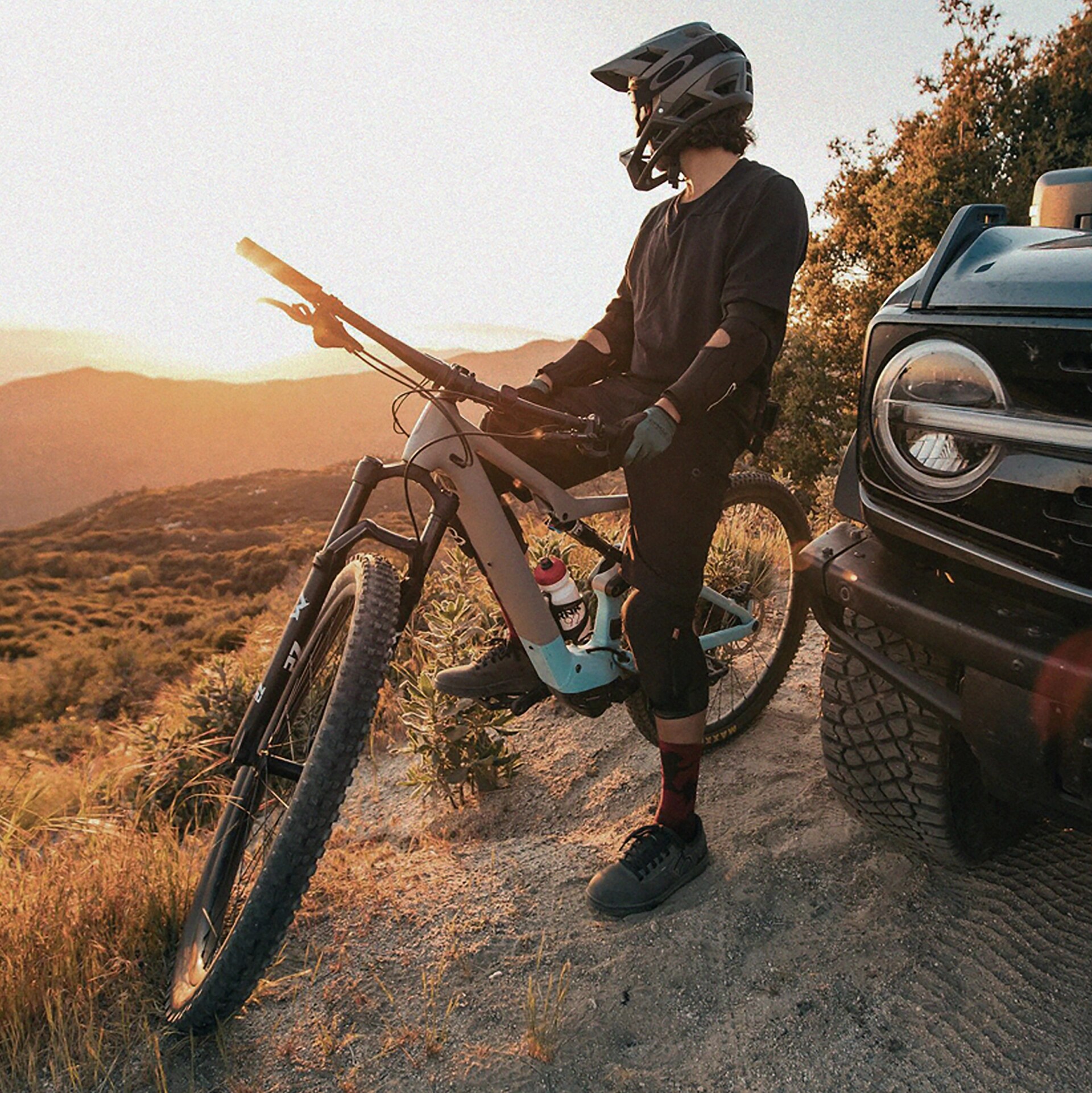 Une personne assise à califourchon sur une moto tout-terrain, vêtue d’un équipement de protection, à côté d’un VUS Ford Bronco® 2026