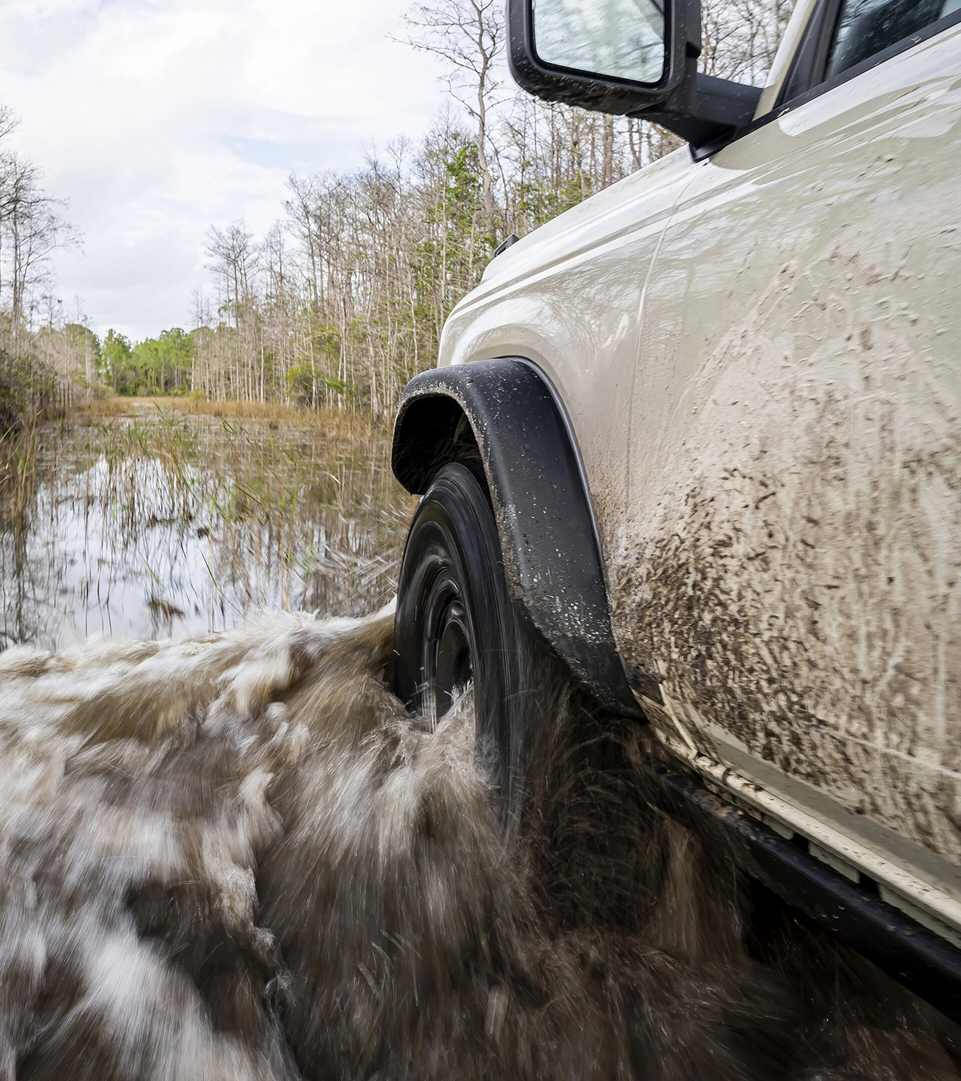 Gros plan sur la roue avant côté conducteur et l’aile d’un VUS Ford Bronco® 2026 alors qu’il traverse une rivière