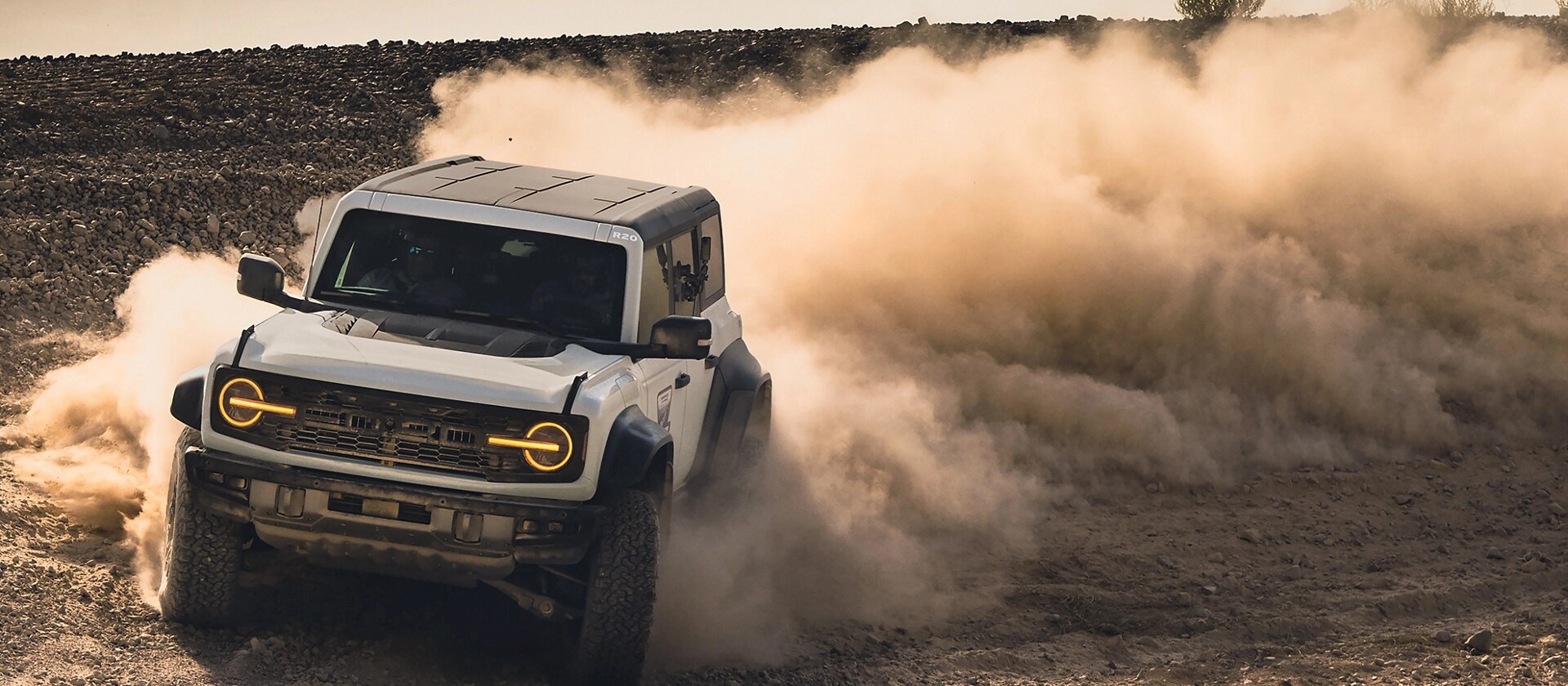 Un VUS Ford Bronco® Raptor® 2026 projetant de la poussière dans un champ vide