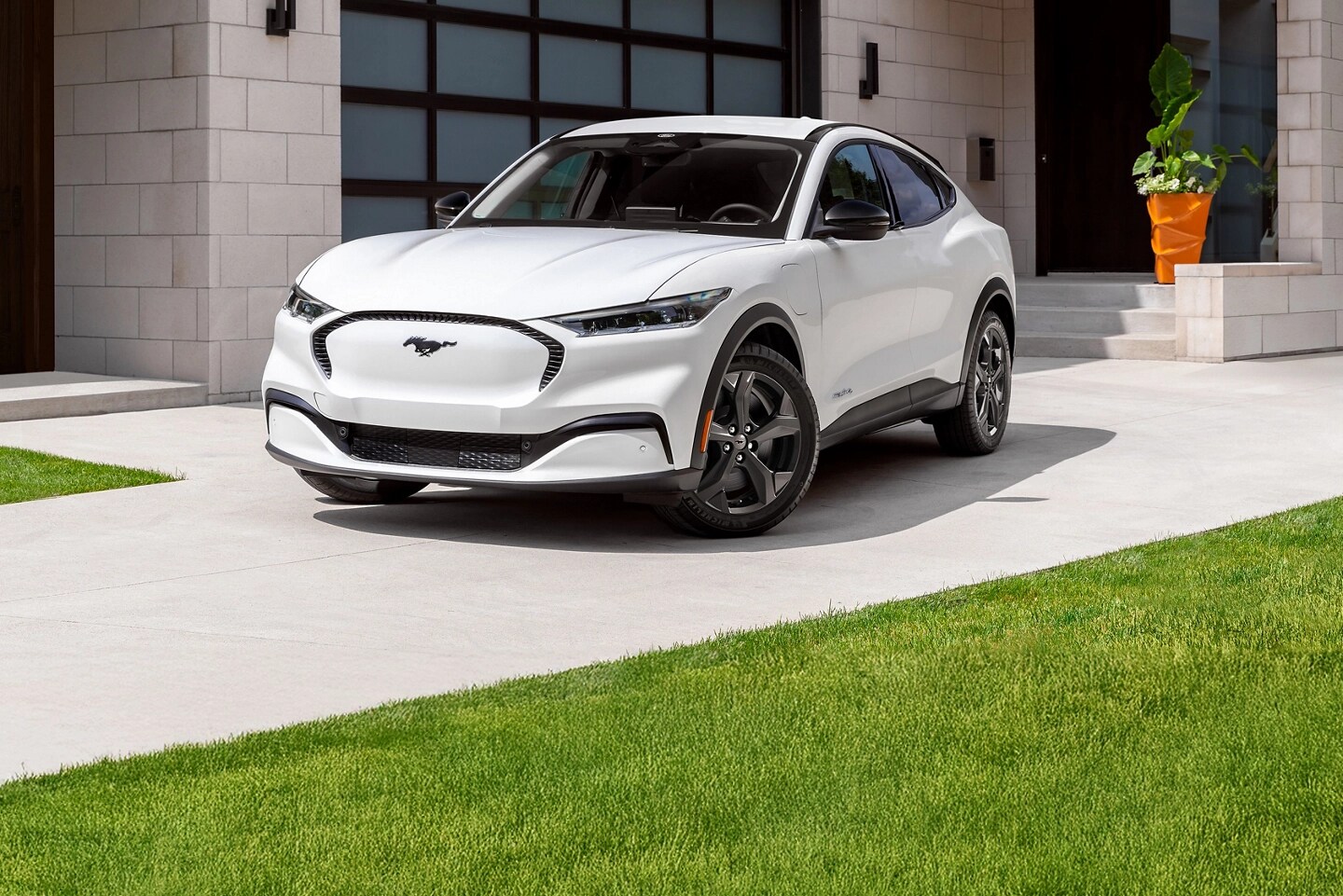 Une Mach E blanche stationnée dans une allée.