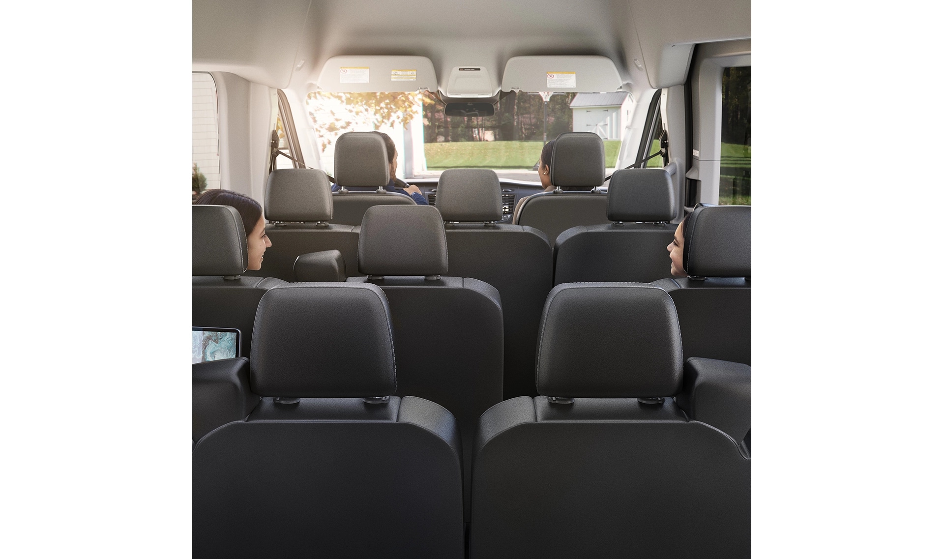 Vue arrière de l'intérieur du Ford Transit avec tous les sièges en position verticale et quatre passagers à l'intérieur.