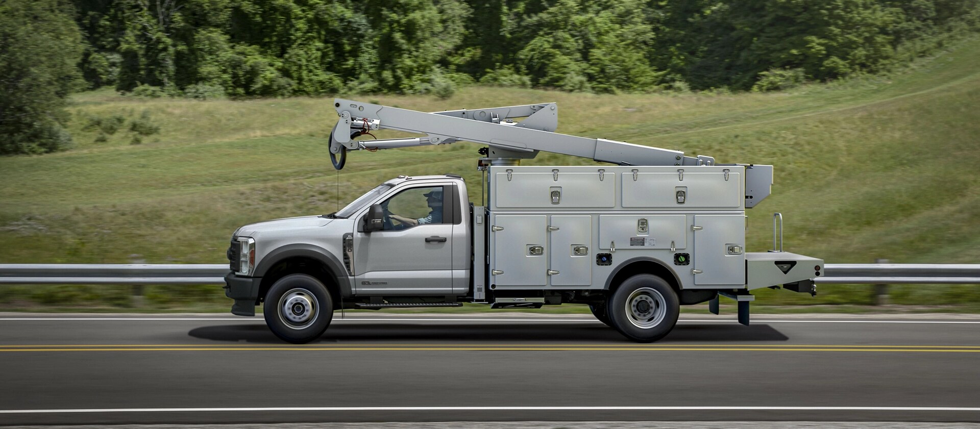 Un Ford Super Duty® à châssis-cabine 2026 avec une rallonge de flèche et un caisson utilitaire circulant sur une route