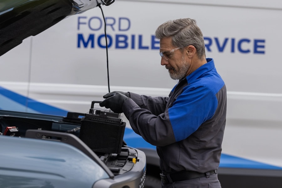 Un technicien de service Ford travaille sur le moteur d’un véhicule. 
