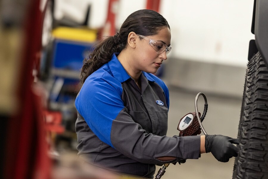 Un technicien de service Ford travaille sur le pneu d’un véhicule surélevé. 