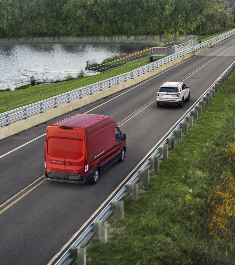 Une Ford E-Transit™ 2025 rouge circulant sur une autoroute de campagne