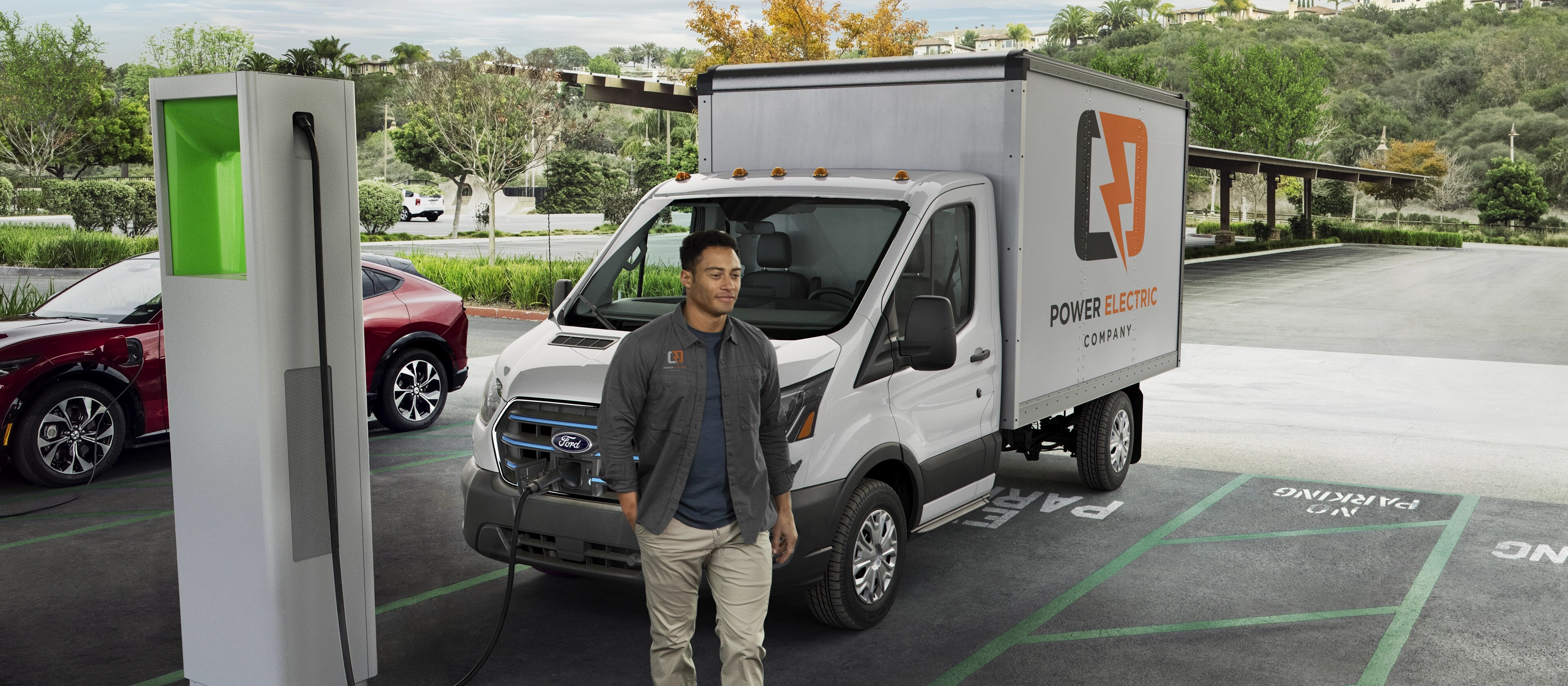 Une Ford E-Transit™ 2025 blanche stationnée en train de se recharger dans un terrain public