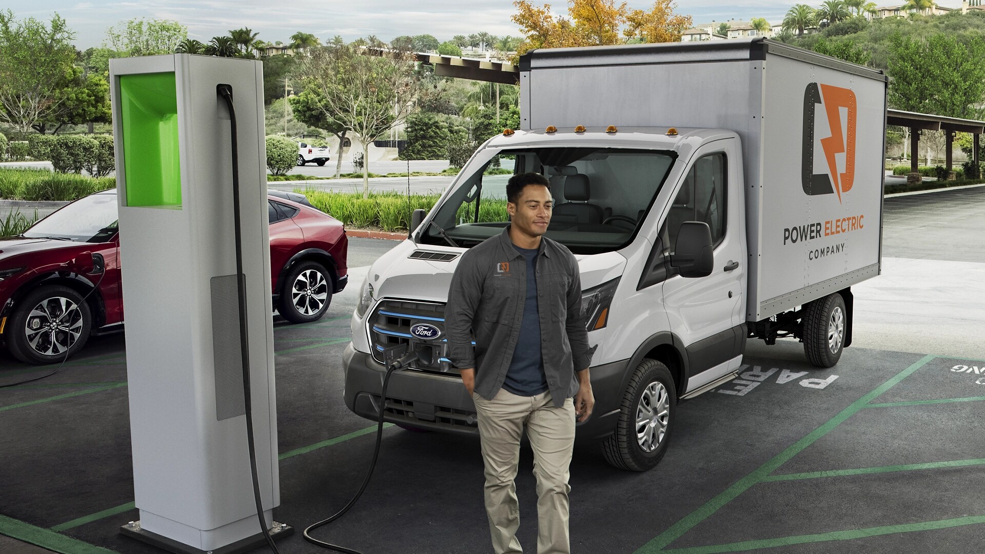 Une Ford E-Transit™ 2025 blanche stationnée à une station de recharge publique