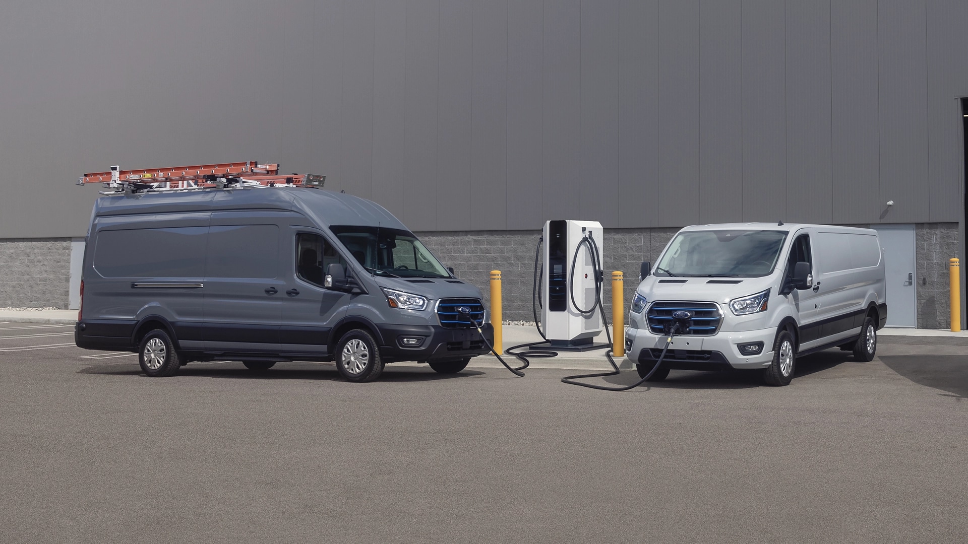 Deux véhicules Ford E-Transit™ 2025 stationnés à une station de recharge publique