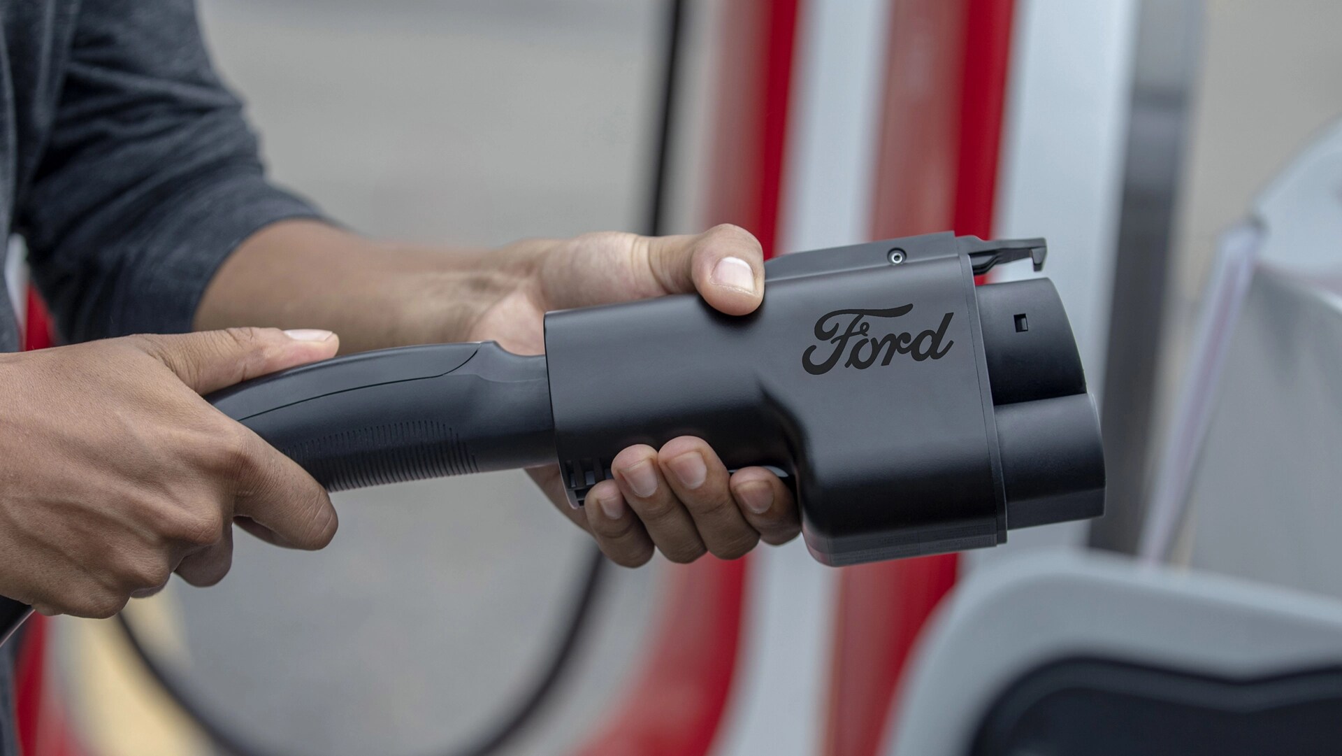 Personne utilisant l'adaptateur de recharge du NACS pour un superchargeur Tesla