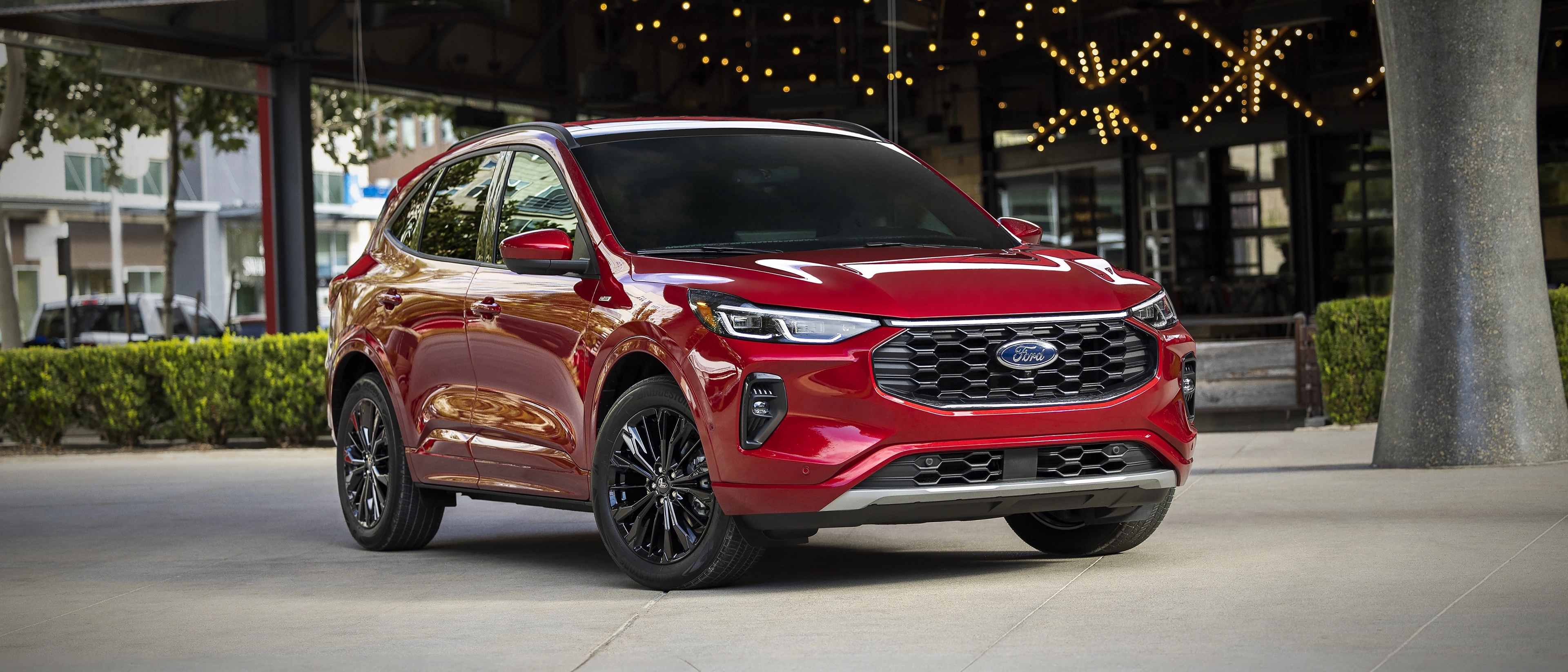 VUS Ford Escape® 2026 en rouge rapide stationné devant un bâtiment décoré de guirlandes lumineuses