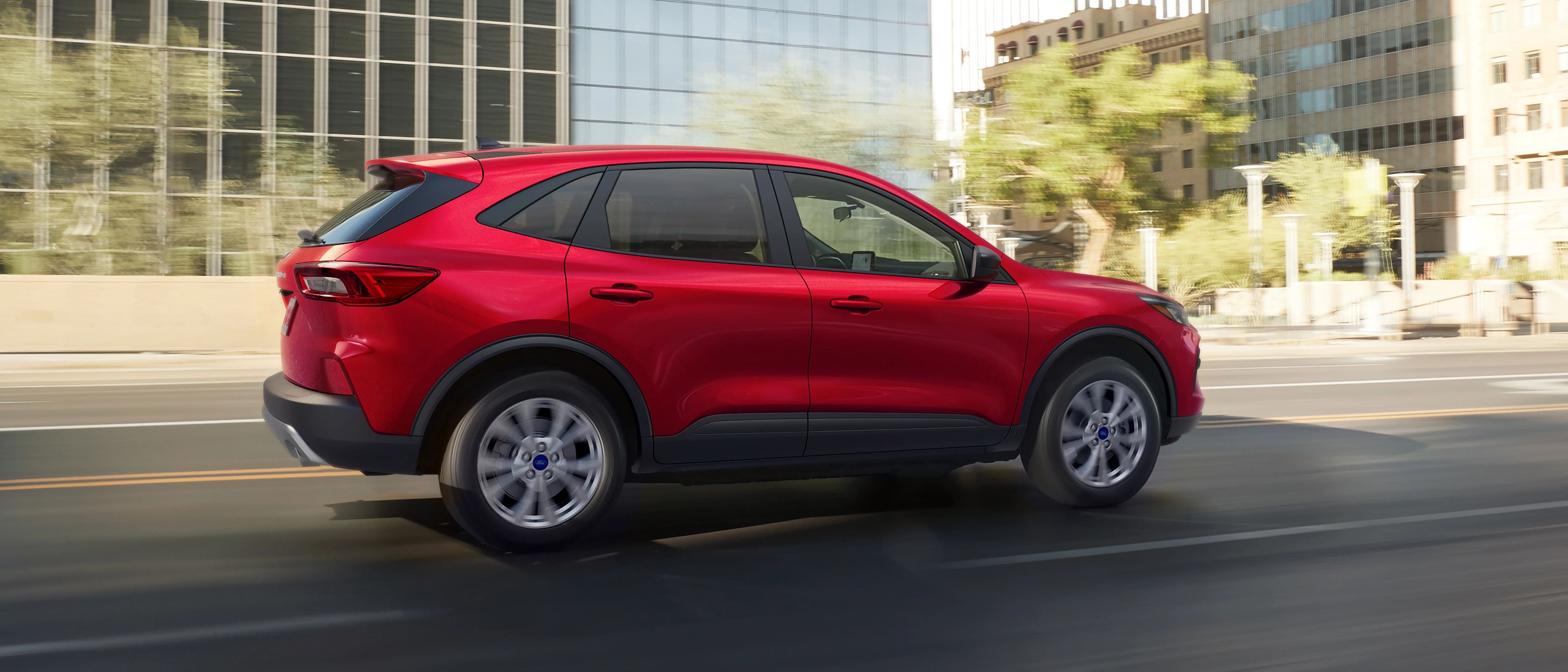 Le VUS Ford Escape® 2026 en rouge rapide conduit sur la rue d’une ville