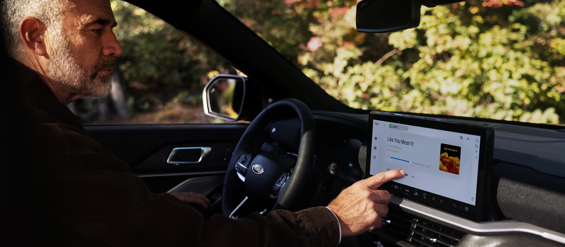Un conducteur avec son doigt sur l’écran tactile de la console centrale dans un VUS Ford Explorer® 2025