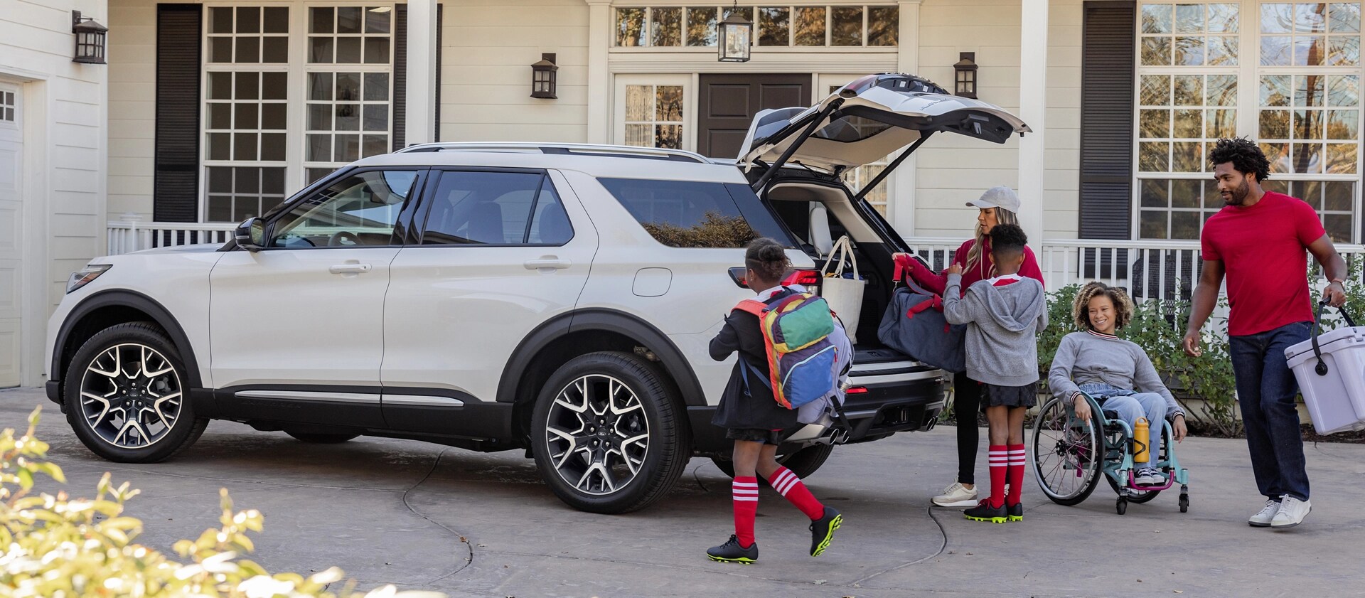 VUS Ford Explorer® 2025 stationné dans l’entrée avec une famille debout à l’extérieur du véhicule