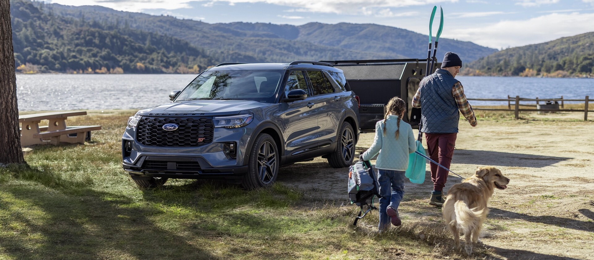 Ford Explorer® 2025 stationné près d’un lac avec une famille debout à l’extérieur du véhicule