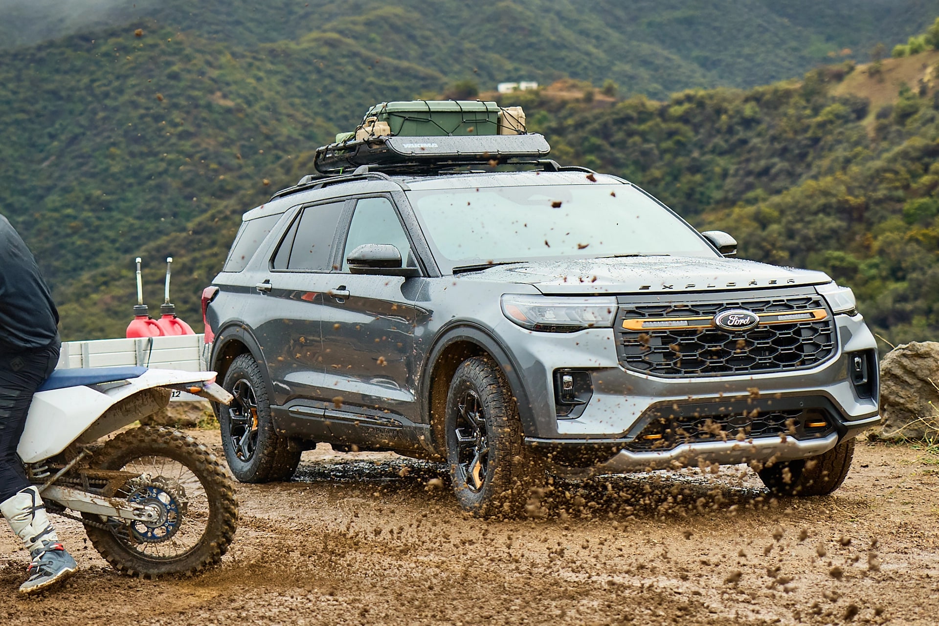 Des personnes roulant à moto dans la boue près d'un VUS Ford Explorer® 2026.