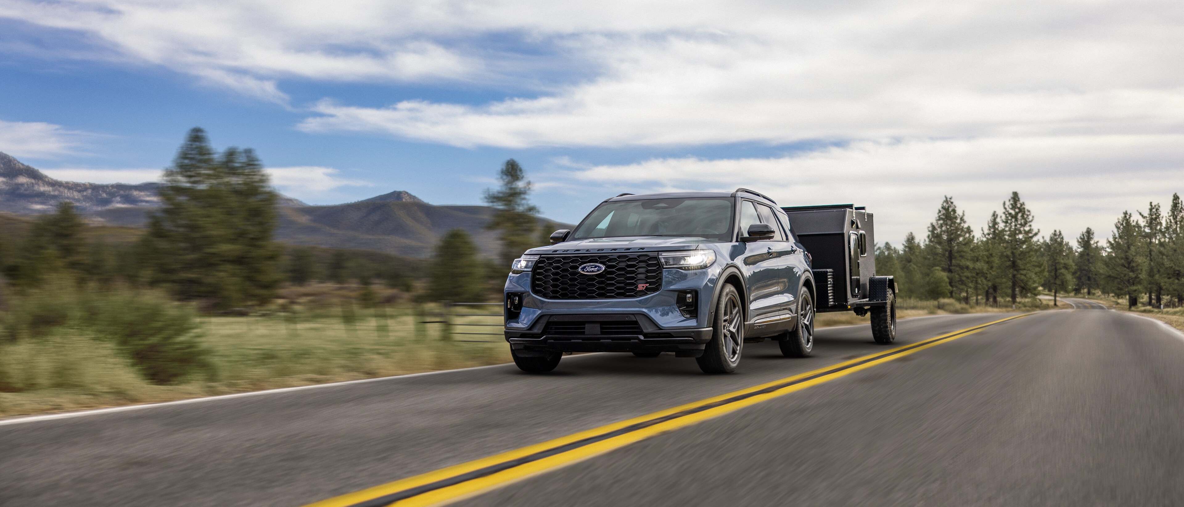 Un VUS Ford Explorer® 2026 tirant une remorque sur une autoroute à travers les montagnes
